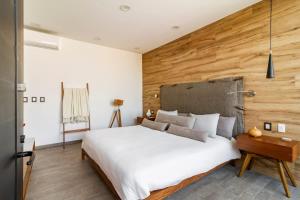 a bedroom with a large white bed and a wooden wall at Rooftop & Private Pool Property Family in Guadalajara