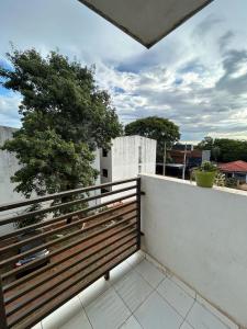 un balcón con una valla de madera y un árbol en Departamento CS, en Encarnación
