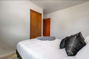 a bedroom with a white bed with a black pillow at The Coal Stone throw away from Red Deer River 2BR House in Drumheller +32 photos