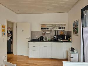 a kitchen with white cabinets and a woman standing in the doorway at Apartment im Paradies jetzt mit Wallbox in Werther