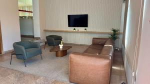 a waiting room with a couch and chairs and a tv at Splendor Thermas in Caldas Novas
