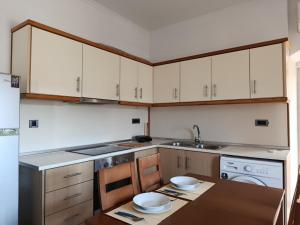 a kitchen with white cabinets and a table with bowls on it at Doukissa's Apartment in Symi +14 photos