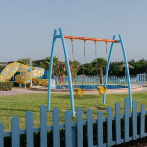 a playground with swings and slides in a park at One Resort Jockey Monastir in Monastir