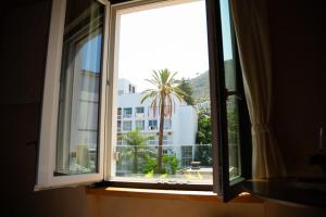 a window with a view of a palm tree and a building at Essenza Boutique Apartments in Cefalù