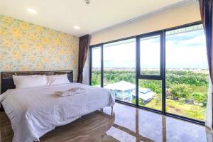 a bedroom with a bed and a large window at Arunsakhon luxury condo in Ban Khok Kham