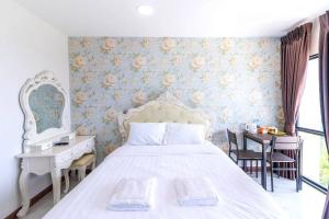 a bedroom with a white bed and a table and chairs at Arunsakhon luxury condo in Ban Khok Kham