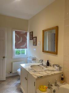 ein Badezimmer mit Waschbecken, Toilette und Spiegel in der Unterkunft Fordie East Cottage in Comrie