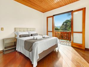 a bedroom with a large bed and a balcony at Capivari Lareira Harry Potter Baden Baden in Campos do Jordão