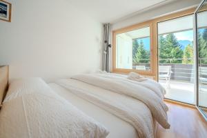 a bedroom with a bed and a large window at Alexandra 120 by Arosa Vacations, Renoviertes Studio mit Bergblick & Parking im Zentrum in Arosa