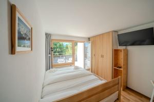 a bedroom with a bed and a window at Alexandra 120 by Arosa Vacations, Renoviertes Studio mit Bergblick & Parking im Zentrum in Arosa