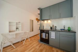 a kitchen with gray cabinets and a table and chairs at Alexandra 120 by Arosa Vacations, Renoviertes Studio mit Bergblick & Parking im Zentrum in Arosa
