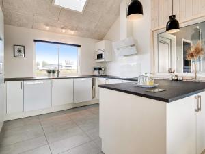 a kitchen with white cabinets and a large window at 18 person holiday home in Ringkøbing in Ringkøbing