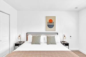 ein weißes Schlafzimmer mit einem großen Bett mit zwei Nachttischen in der Unterkunft Private Jungle Pool Home - Arcade Games & Pool in Fort Lauderdale + 88 Fotos