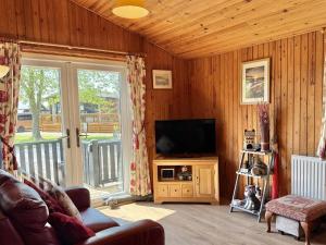 Una sala de estar con televisión y balcón. en Oakwood 1, en Rousdon