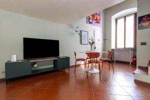 a living room with a tv and a table and chairs at Arrivederci Apartment in Bergamo