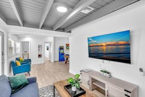 ein Wohnzimmer mit einem Sofa und einem Fernseher an der Wand in der Unterkunft Private Jungle Pool Home - Arcade Games & Pool in Fort Lauderdale