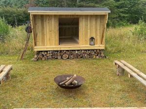 a wooden cabin with a fire pit in the grass at 6 person holiday home in Blokhus-By Traum in Blokhus