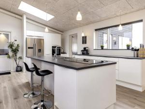 a kitchen with white cabinets and a large island with stools at 5 star holiday home in Væggerløse in Bøtø By +49 photos
