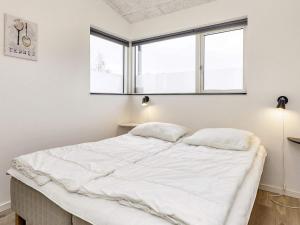 a bedroom with a bed with white sheets and two windows at 5 star holiday home in Væggerløse in Bøtø By