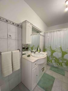 a white bathroom with a sink and a shower at Casa Santo António in Água de Alto