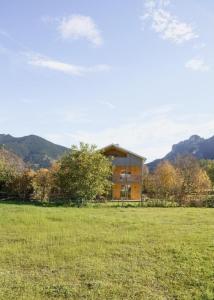 a house in the middle of a field with mountains in the background at Ferienwohnung Bergufer - Studio im Souterrain in Oberammergau