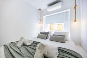 a white bedroom with a large bed with pillows at Cozy House Portimao Centre in Portimão