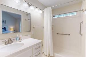 a white bathroom with a sink and a shower at Camellia by Wolf Pen in College Station
