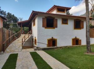 a white house with brown doors and a yard at Sinta a Ilha mais Bela - 150m das praias do Viana e Siriúba in Ilhabela +6 photos