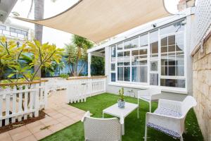 Un patio al aire libre con sillas blancas y una mesa. en Secret on Suffolk - Chic Fremantle home, en Fremantle