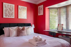 a red bedroom with a bed with towels on it at The Rainbow Retreat by Sheppey Stays in Iwade