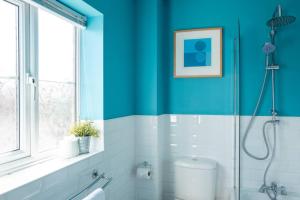 a bathroom with blue walls and a glass shower at The Rainbow Retreat by Sheppey Stays in Iwade +40 photos