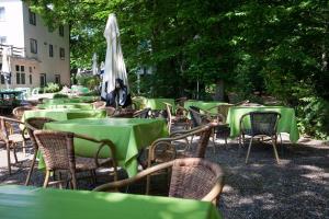 eine Gruppe von Tischen und Stühlen mit grünen Tischen und einem Regenschirm in der Unterkunft Hotel Aquarius Braunschweig in Braunschweig