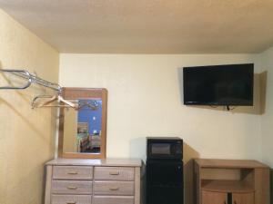 a room with a tv on a wall with a dresser and a lamp at Blarney Inn in Shamrock