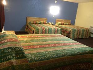 2 Betten in einem Hotelzimmer mit bunten Decken in der Unterkunft Blarney Inn in Shamrock