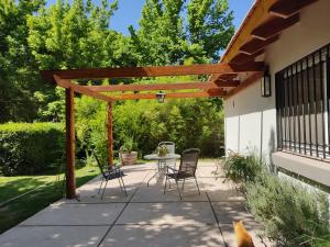 a patio with a table and chairs under a wooden pergola at Old Willow in Chacras de Coria