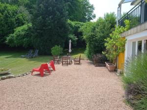 a patio with red chairs and tables in a yard at Vacation Home in France with Pool in Chaumard