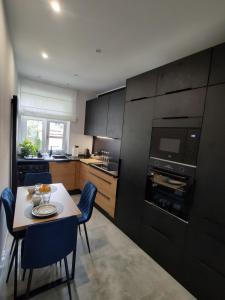 a kitchen with a table and blue chairs in a room at Cozy Calming Apartment in Poznań