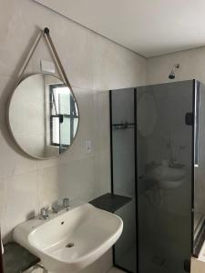 a bathroom with a sink and a shower and a mirror at Flat perto da praia com piscina na cobertura in São Vicente