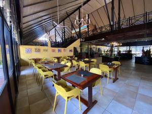 a restaurant with wooden tables and yellow chairs at Senegambia Beach Hotel in Kololi