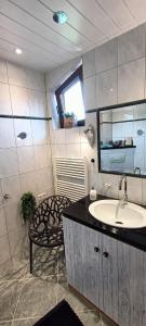 a bathroom with a sink and a mirror and a chair at Ferienwohnung Terrassenzeit in Illingen