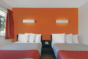 2 letti in una camera con parete arancione di Motel 6 San Jose CA South a San Jose