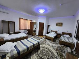 a bedroom with three beds and a rug at Sadaf Hotel in Guliston
