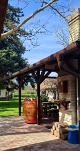 a wooden pavilion with a barrel and a picnic table at Lassu Tanya Vendégház in Nagykőrös