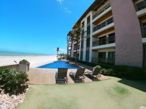 a building with chairs and a swimming pool next to the beach at Varandas do Mar pé na areia in Cumbuco