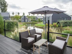 a deck with chairs and an umbrella and a table at Chalet in Kattendijke near Eastern Scheldt in Kattendijke