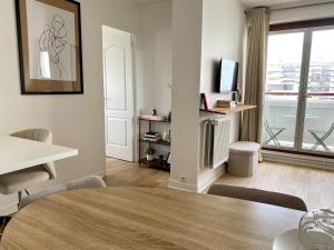 a white living room with a table and a television at Eiffel Tower View & Pool in Paris