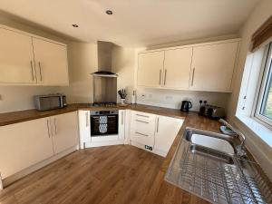 a kitchen with white cabinets and a sink at Luxury Riverside Retreat In Picturesque Setting in Clunton +6 photos