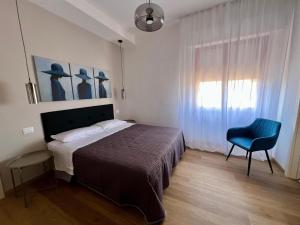 フォリーニョにあるFoligno City Roomsのベッドルーム1室(ベッド1台、青い椅子付)