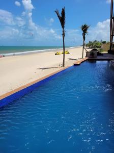a blue swimming pool next to a beach at Varandas do Mar pé na areia in Cumbuco