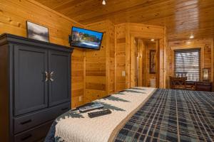 a bedroom with a bed and a tv on the wall at Bear Pause Cabin by American Patriot Getaways in Glade +31 photos